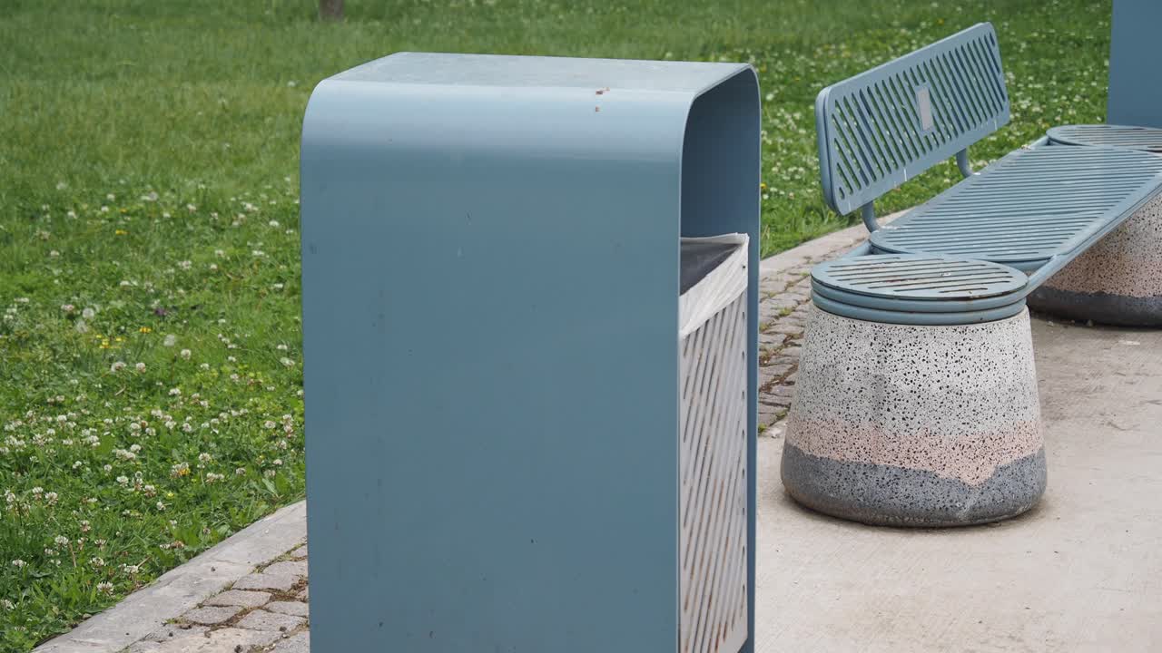 파란색 쓰레기통과 공원의 벤치