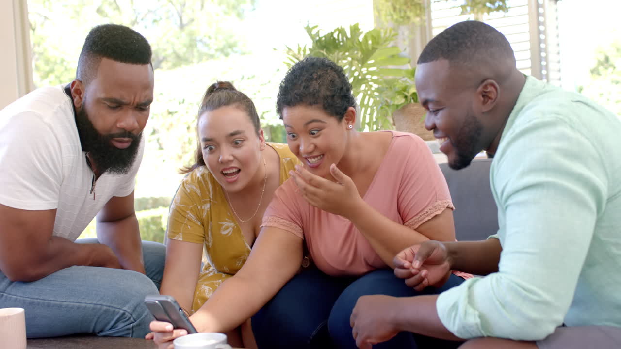 diverse friends gathered around smartphone, laughing and enjoying time together indoors