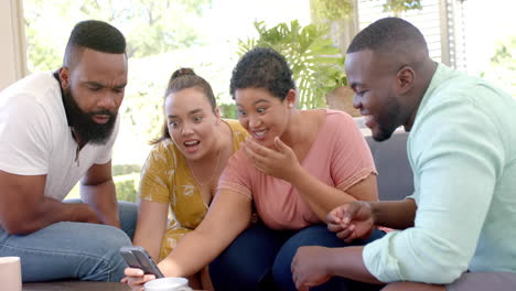 diverse friends gathered around smartphone, laughing and enjoying time together indoors