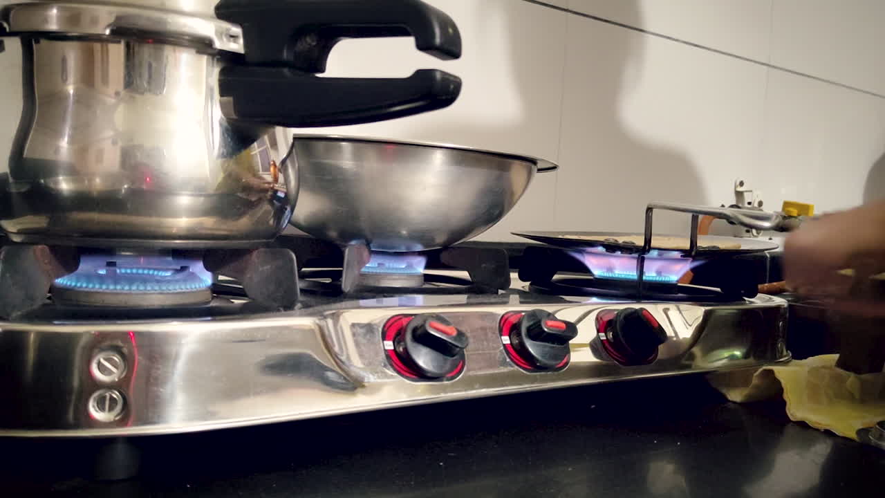 Gas stove blue flames burning cooking pots pans Indian kitchen daily home cooking scene energy use blue flame clean burn stainless steel cookware pressure cooker wok setup