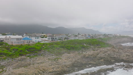 Casas-Unifamiliares-A-Costa-Del-Mar.-Olas-Que-Lavan-Rocas-Escarpadas-Y-Dentadas.-Nubes-Bajas-Que-Esconden-Montañas-En-El-Fondo.