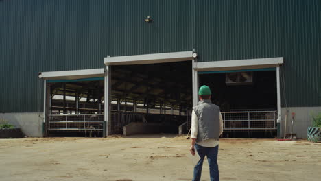 worker walking livestock farm facility holding clipboard. milk product industry.