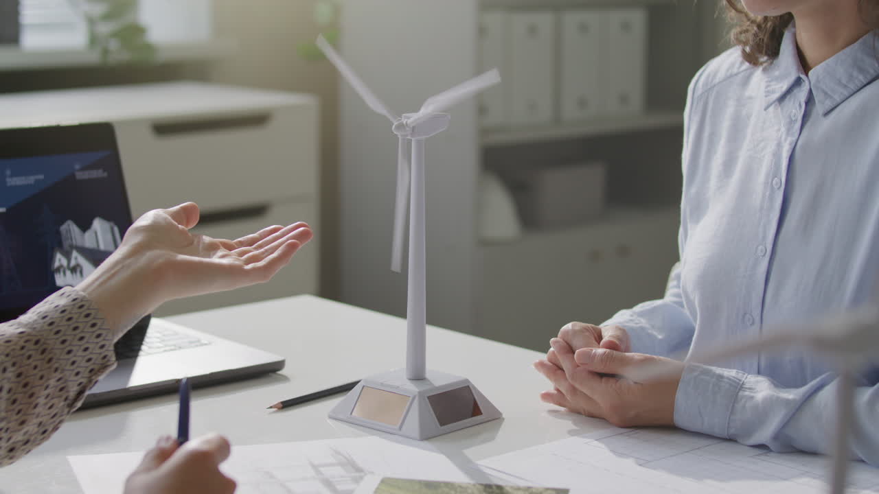 Renewable Energy Engineers Discussing Wind Turbine Model at Business Meeting