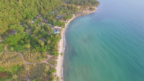 drone de isla tropical, fotografiado con exuberante selva tropical y palmeras tropicales con playa de arena blanca y costa rocosa