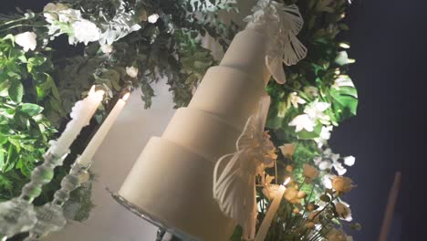 Large-white-wedding-cake-in-front-of-green-foliage-decoration