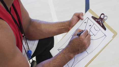 Männlicher-Afroamerikanischer-Basketballtrainer-Mit-Notebook-In-Der-Halle,-In-Zeitlupe