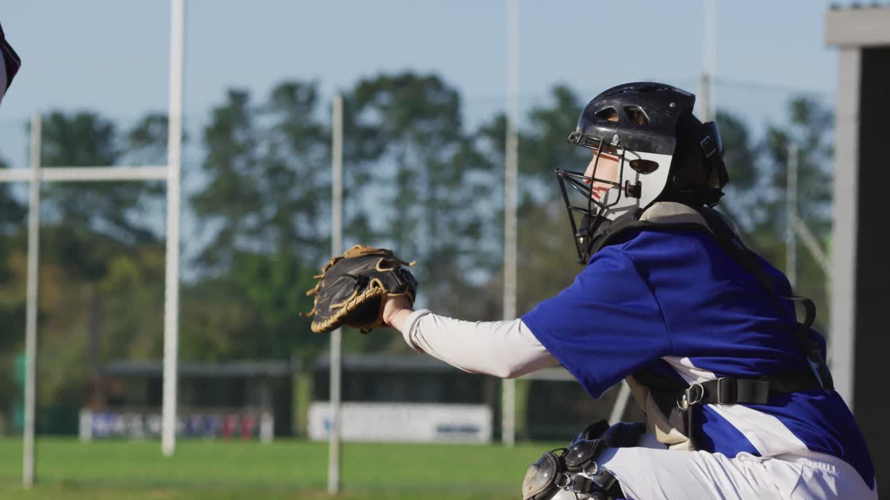 Giocatrice di baseball caucasica in posizione di ricevitore che afferra la palla su un campo da baseball.