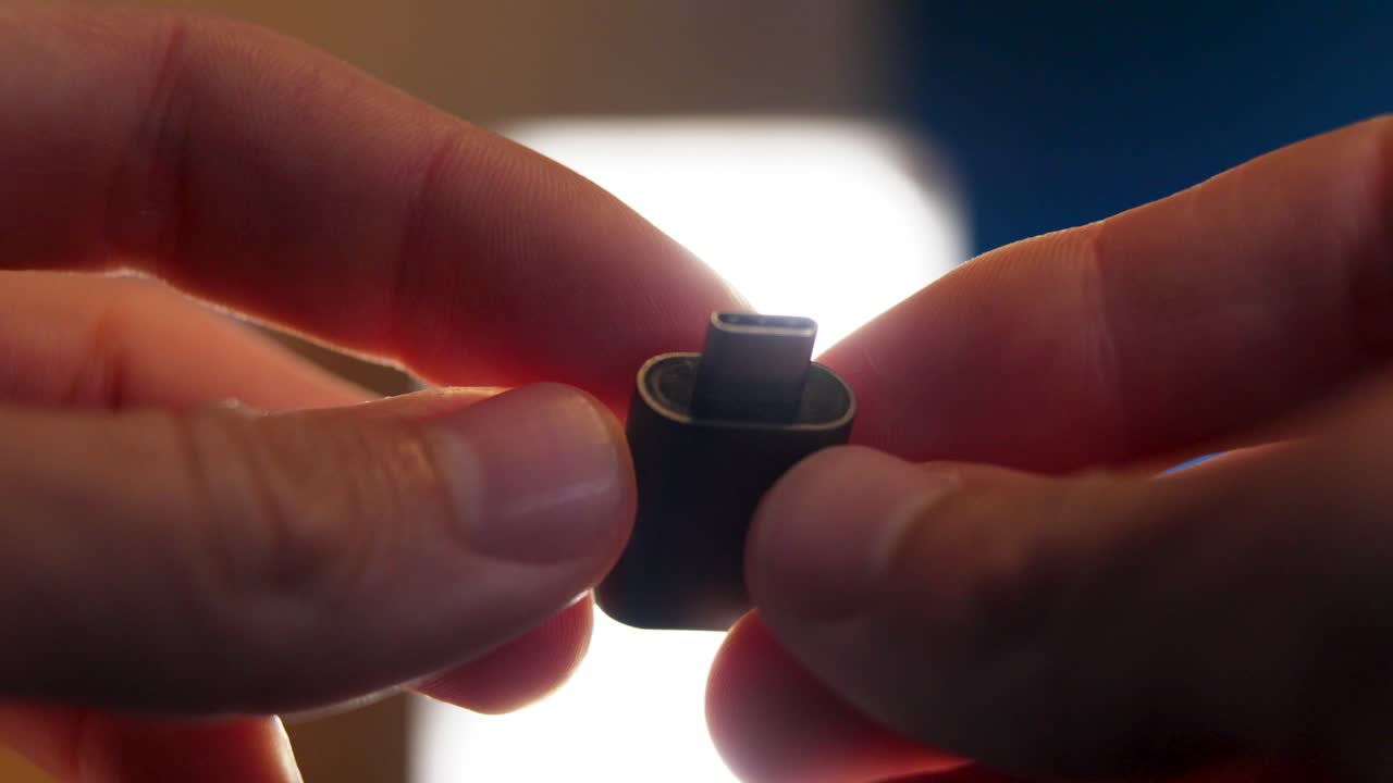 Close-up of hands holding and showcasing a USB-C adapter, emphasizing modern technology and connectivity. Captures the small-scale design and functionality of the device.