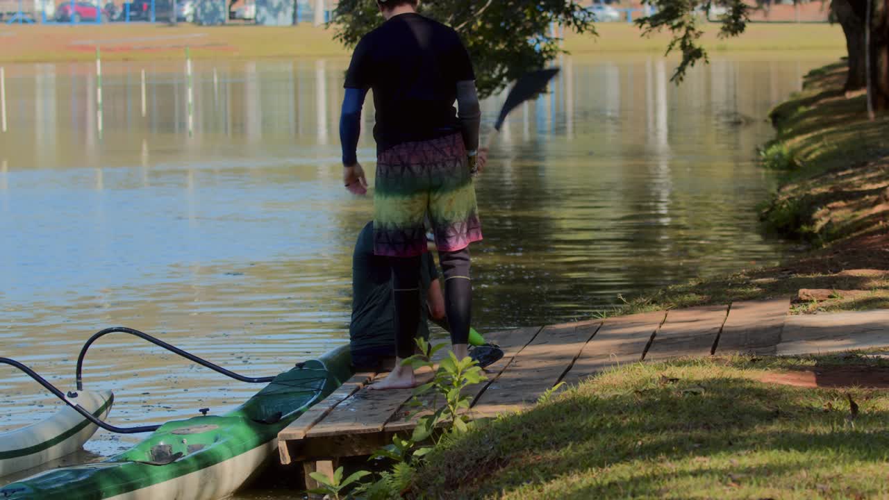 Men preparing for kayaking or paddleboarding on a dock by the lake