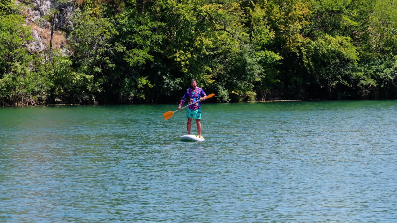 Ritratto di un uomo in piedi su una tavola da paddleboard sul fiume Mreznica in Croazia. Scatto aereo