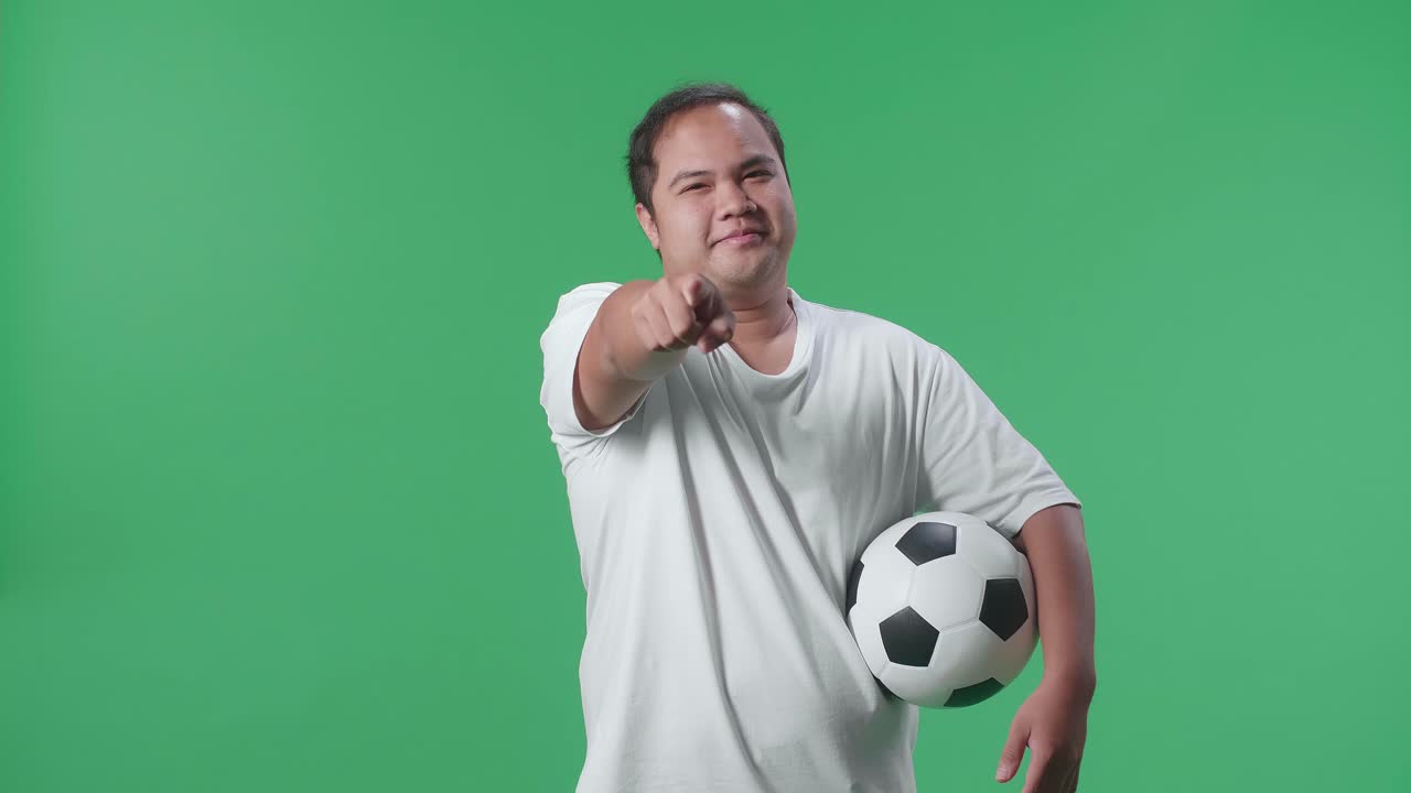 hombre sosteniendo una pelota de fútbol y apuntando
