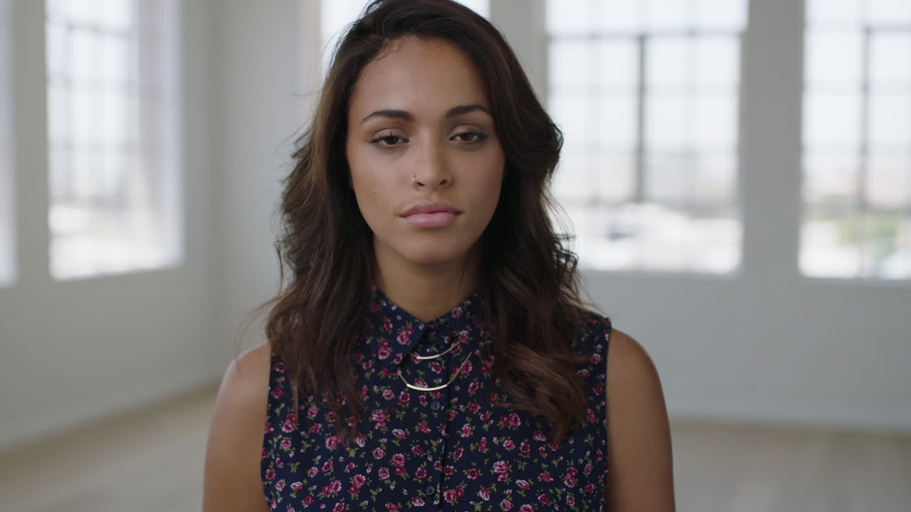 retrato en primer plano de una joven hispana atractiva que parece seria y pensativa ante la cámara con una hermosa blusa floral