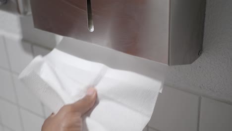 using a paper towel dispenser in a restroom