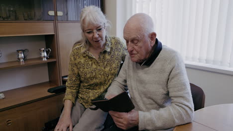senior man using tablet with caregiver