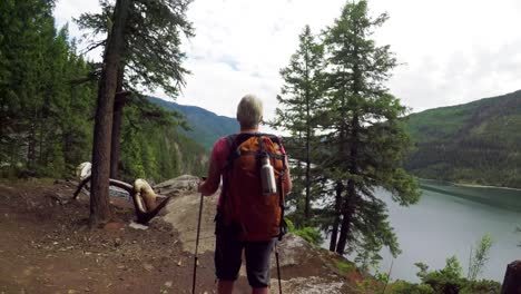 mature woman with hiking pole standing at riverside 4k