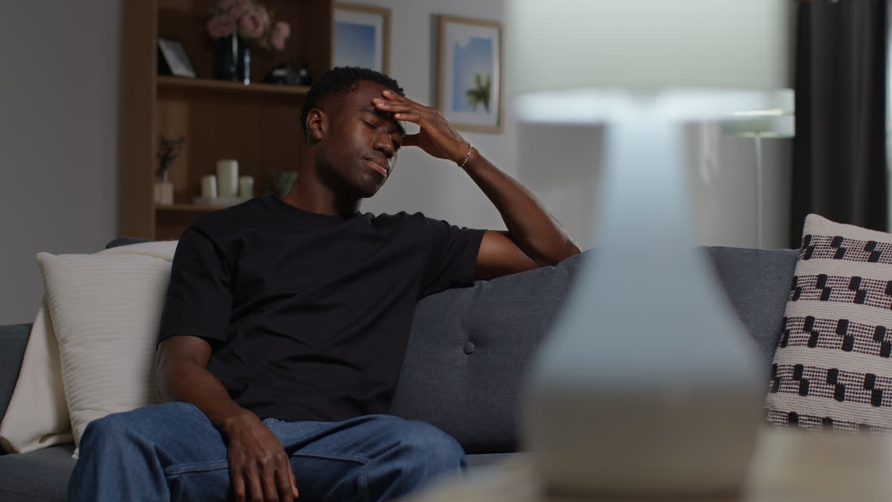 Unhappy And Depressed Young Man Sitting On Sofa At Home Looking Anxious And Worried Resting Head On Hand 4