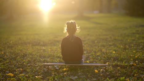 girl sitting on a skateboard in a park at sunset