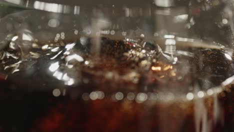 Macro-shot-of-ice-cubes-falling-in-a-glass-of-cola-in-slow-motion