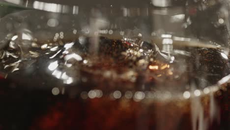 macro shot of ice cubes falling in a glass of cola in slow motion