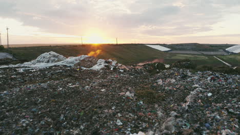 high-quality footage of flyover above trash by sunset, with steam rising from the garbage, showcasing dramatic environmental themes and nature's interaction with waste