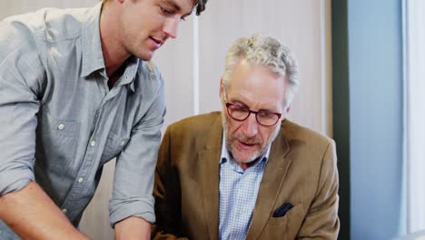 businessman and coworker discussing over laptop
