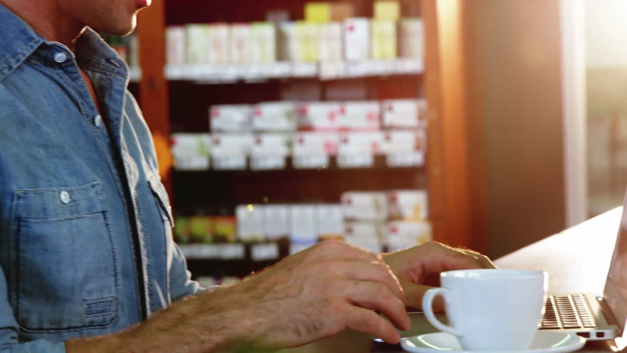 Uomo che usa il laptop mentre prende un tè in un caffè