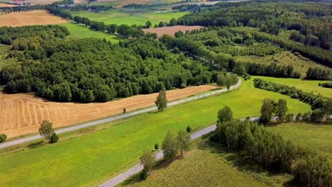 aerial shot of curvy country road surrounded by fields and trees