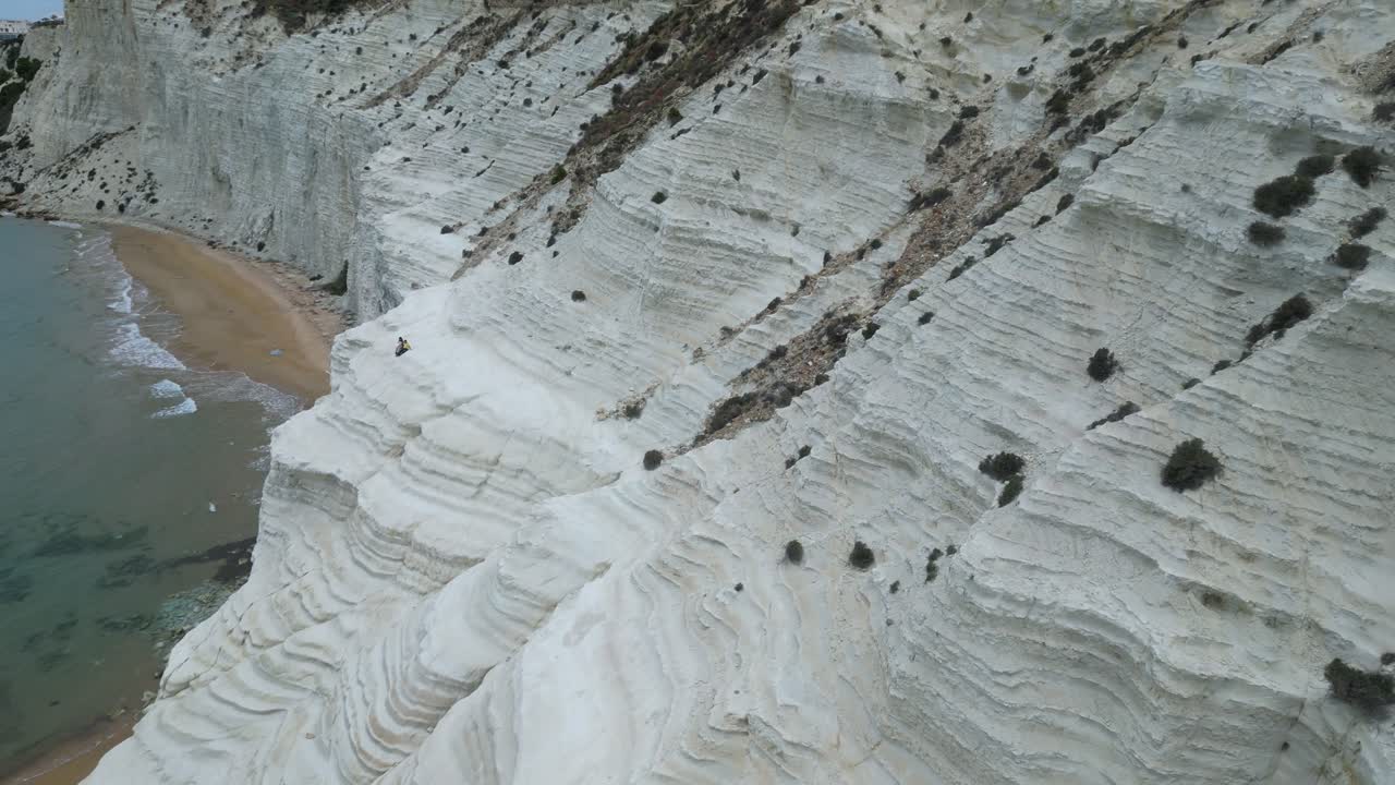 Aerial drone footage of Scala dei Turchi, Sicily: white marl cliffs descending into turquoise sea, coastal waves and dramatic Mediterranean light. Ideal for travel, nature, and heritage projects