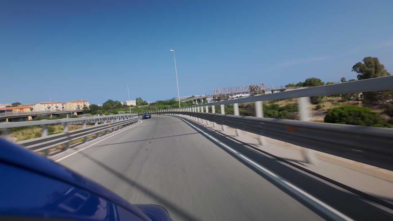 Scenic highway view with city skyline, blue road markings, and clear skies.