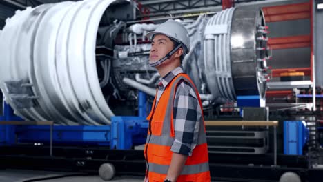 side view of asian male engineer with safety helmet looking around while standing with airplane engine maintenance conducted, analytics checking the turbine