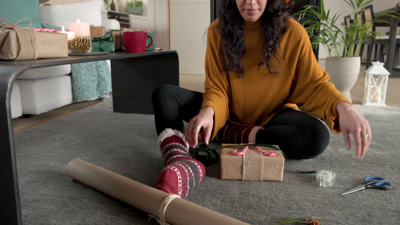 Woman wrapping Christmas gifts at home, smiling and enjoying festive atmosphere, copy space