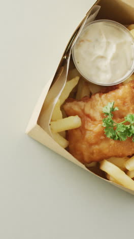 video of fish and chips with dip in takeaway food box, with copy space on white background