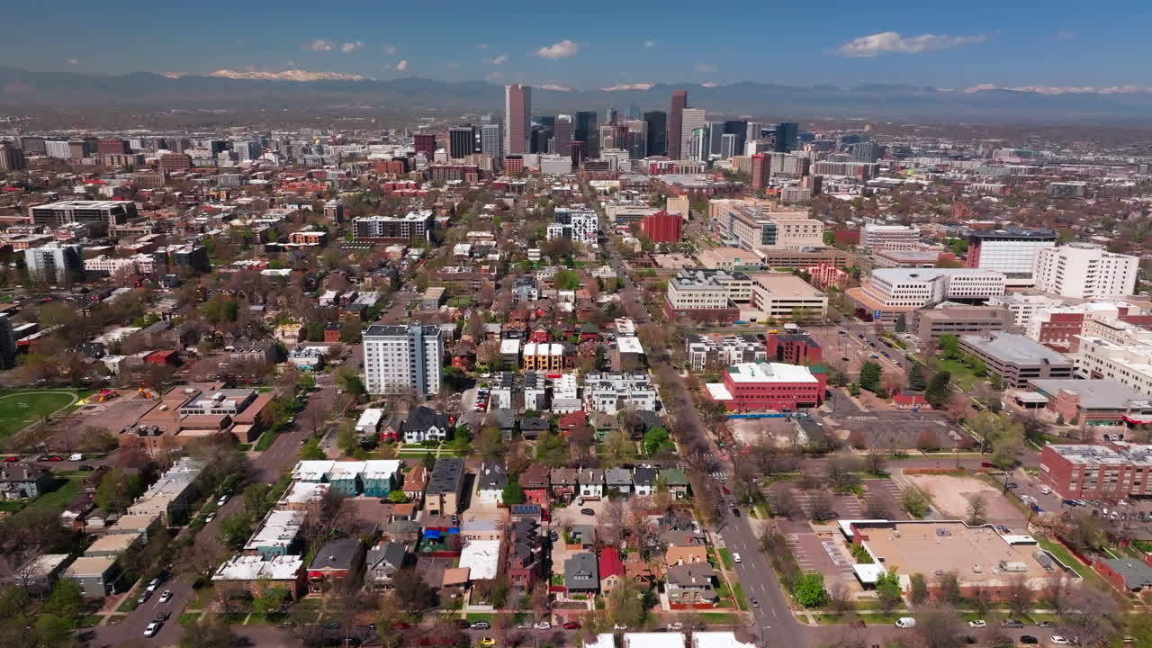 Spring time neighborhood Denver Colorado City Park vibrant spring summer aerial drone sunny blue sky snow capped Rocky Mountains front range cityscape green lush grass trees blossom forward motion
