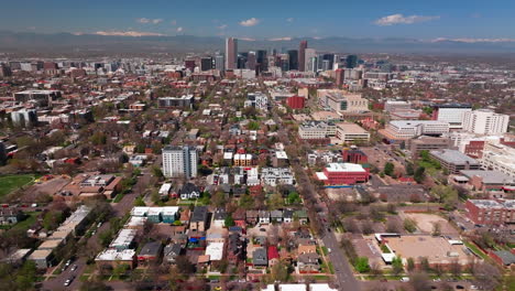 spring time neighborhood denver colorado city park vibrant spring summer aerial drone sunny blue sky snow capped rocky mountains front range cityscape green lush grass trees blossom forward motion