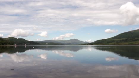 a tranquil scottish loch with reflections of the sky on the water