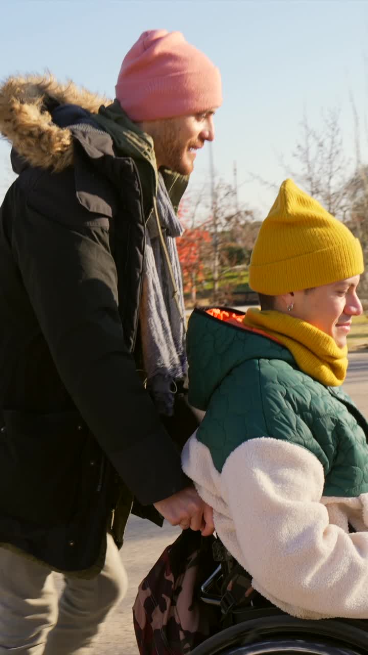 Man Pushing Person in Wheelchair Through Park on a Sunny Day