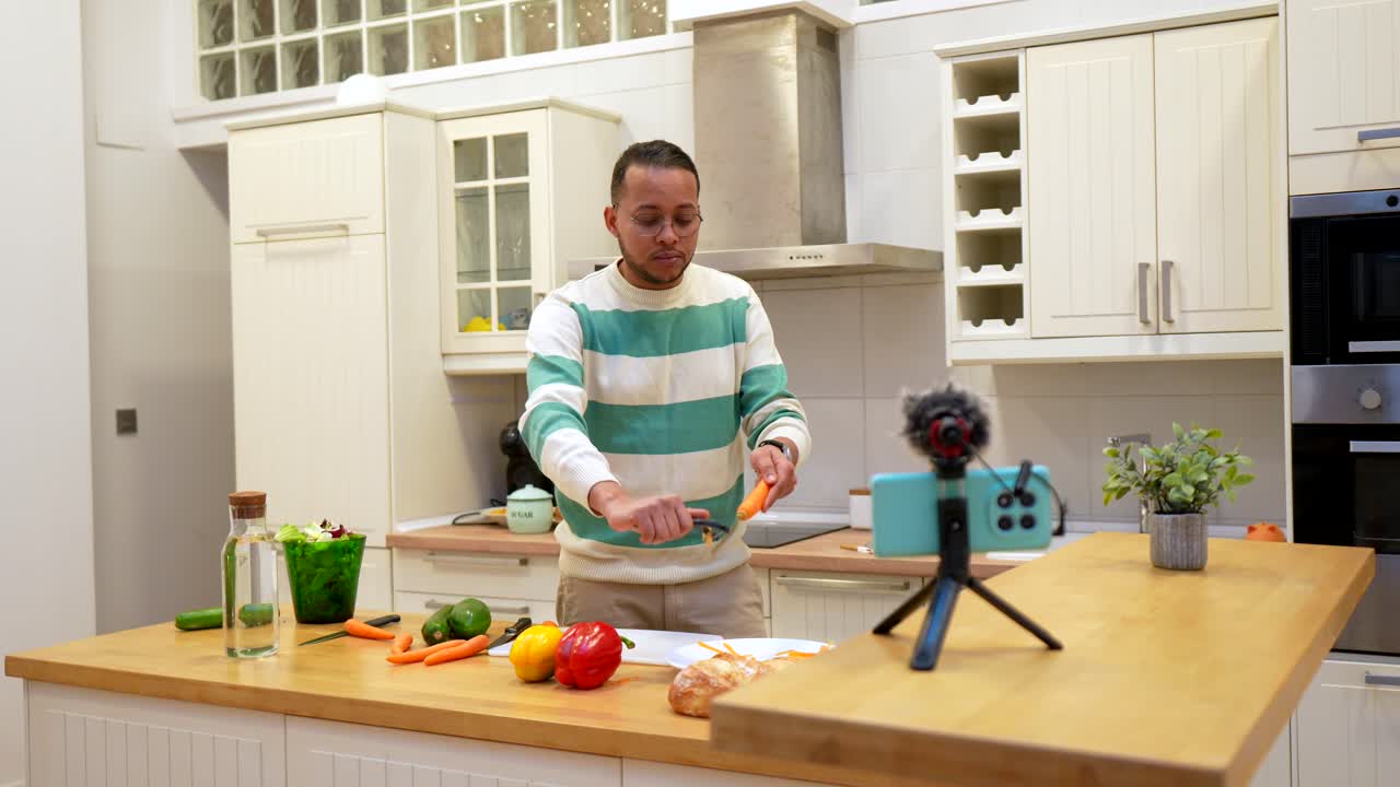 Uomo che pela una carota mentre registra un video di cucina in una cucina moderna