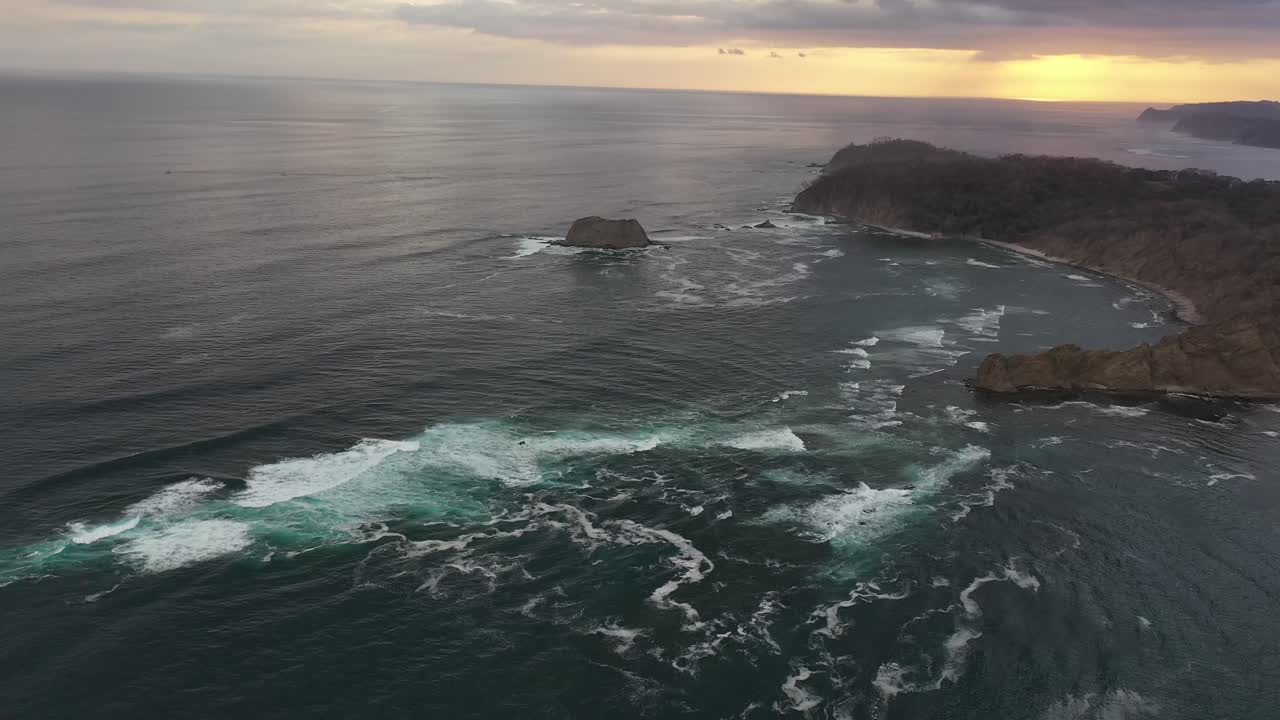 Stillehavskysten i Costa Rica ved solnedgang med klippefyldt odde, luftfoto-flyover