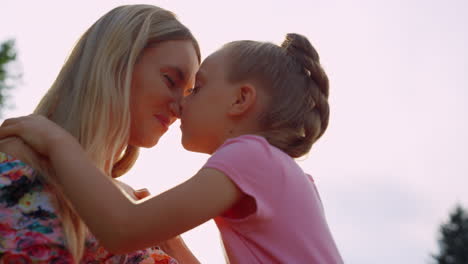 madre y hija lindas mirándose unas a otras en el parque de la ciudad al atardecer