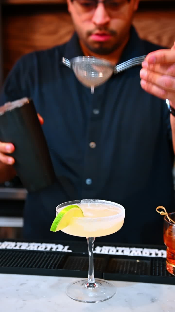 Lime cocktail being strained. Kyiv, Ukraine, 23 August 2025: A lime cocktail being strained into a sugared glass rim in a bar setting