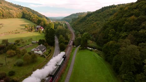 vista aérea de un tren de vapor pasando por un paisaje de otoño