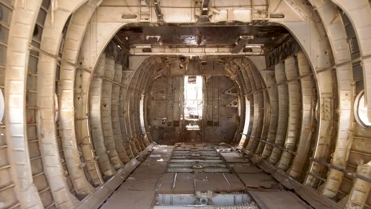 toma aérea de drones del interior de un antiguo monumento de avión del ejército desmantelado colocado en un campo de tierra vacío, vilipendiando una vista de árboles, plantas y un camino de tierra