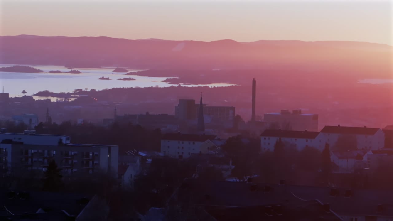 Oslofjord Olso city downtown Norway Norge aerial drone view inner coastline Hovedøya Lindøya islands Norwegian arctic vibrant pink purple hue sunset apartment buildings cityscape parallax circle left