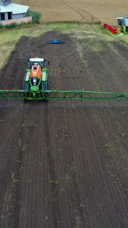 tractor spraying agricultural field. aerial shot of the moderm tractor spraying agricultural field vertical video