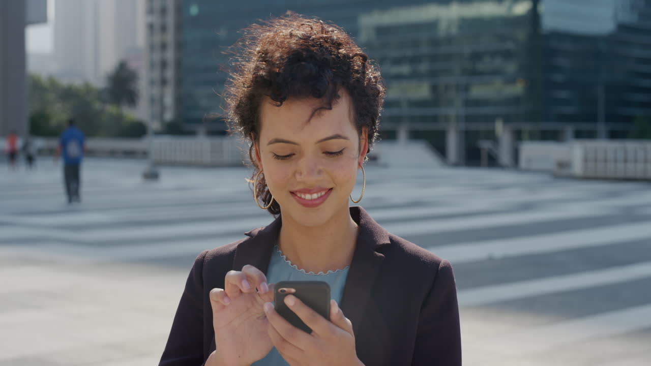 portrait successful young hispanic business woman using smartphone texting browsing messages enjoying mobile phone communication in city slow motion
