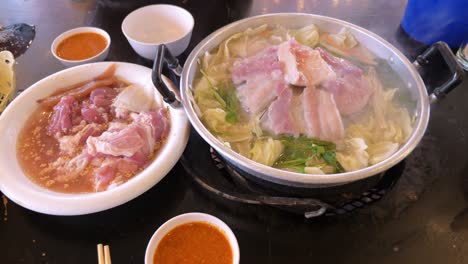 grilling sliced pork and meat on a hot pan asian style with ingredients and sauce