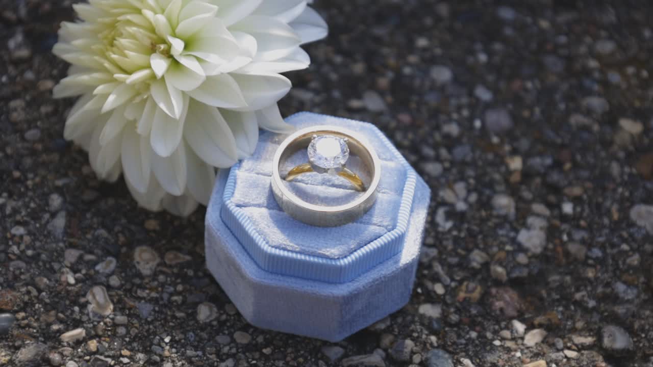 Wedding rings set next to wedding flower