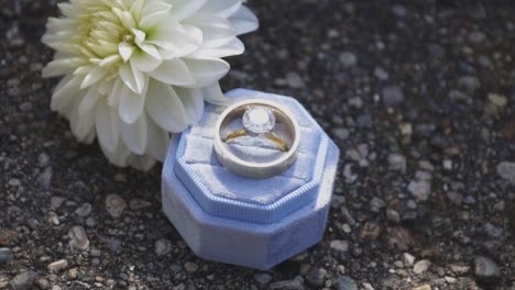 wedding rings set next to wedding flower