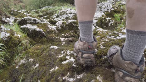 Follow-shot-of-white-legs-in-brown-boots-walking-on-moss-covered-rocks