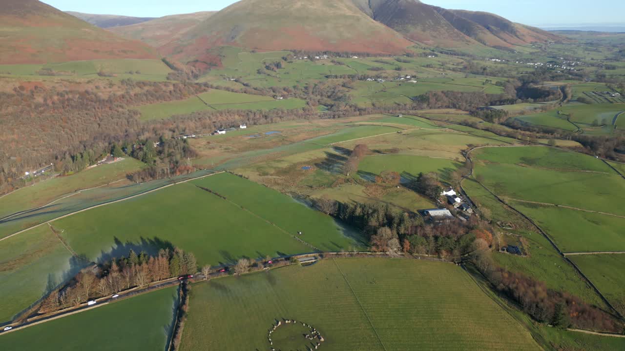 Ancient stone circle from high altitude with camera pan up revealing mountain Blencathra
